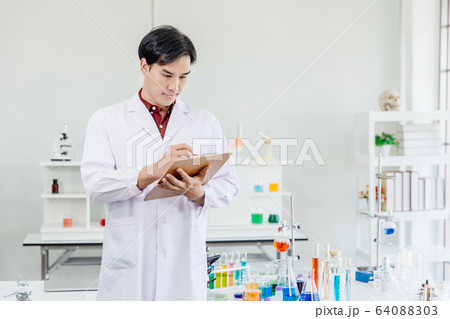 Asian Male Scientist Doctor pay attention working in lab hand taking note or research  64088303