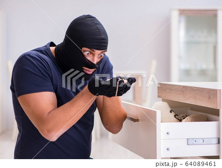 Robber wearing balaclava stealing valuable things 64089461