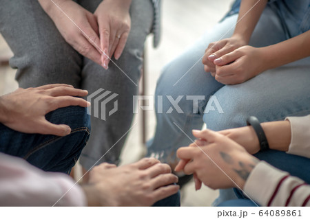Close up picture of people sitting in a circle close to each other Close up picture of people sitting in a circle close to each other 64089861
