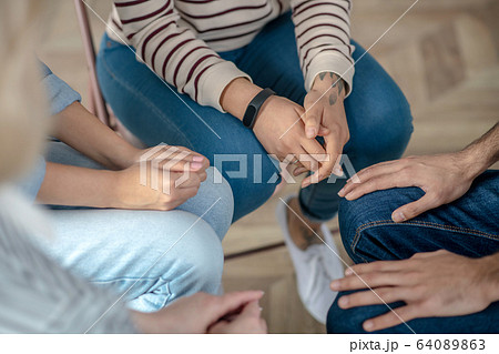 Group of people sitting in a circle close to each other 64089863