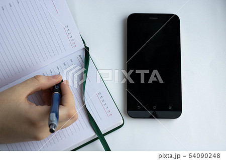 Woman hands writing on book in office.Business woman working on desk of wood.Business woman working with laptop and office supplies on top view.Copy space Woman hands writing on book in office.Business woman working on desk of wood.Business woman working with laptop and office supplies on top view.Copy space 64090248