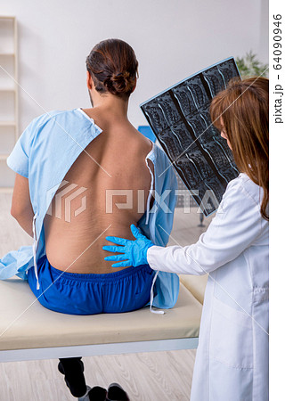 Young back injured man visiting female doctor chiropractor 64090946