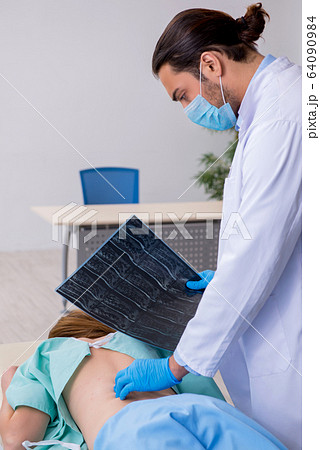 Young back injured woman visiting male doctor chiropractor 64090984