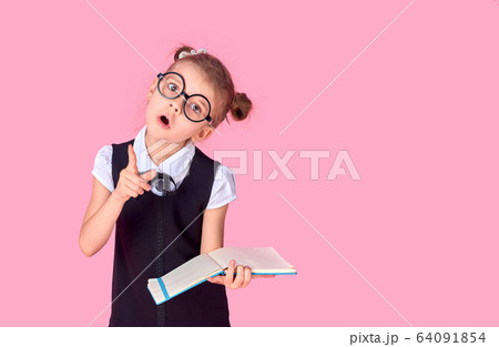 A picture of a schoolgirl with textbook pointing at something over isolate pink background A picture of a schoolgirl with textbook pointing at something over isolate pink background 64091854