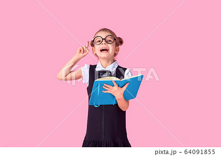 A picture of a schoolgirl with textbook emotionally guessing pointing at something over isolate pink background 64091855