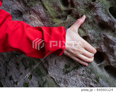 Arm in jacket on weathered sandstone rock. Arm in jacket on weathered sandstone rock. 64093124