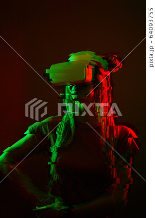 Woman is using virtual reality headset. Neon light studio portrait. Image with glitch effect. 64093755