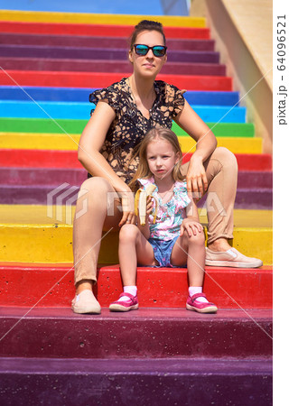 little girl sits on the edge of the wall dangling legs, stone wall her legs dangling in the air 64096521