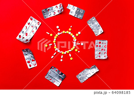 Colored pills, tablets and capsules on a red background - history of treatment, prevention of pandemic 64098185