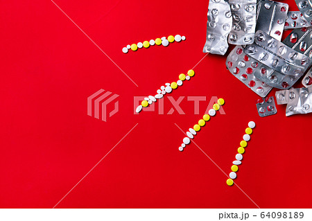Colored pills, tablets and capsules on a red background - history of treatment, prevention of pandemic 64098189