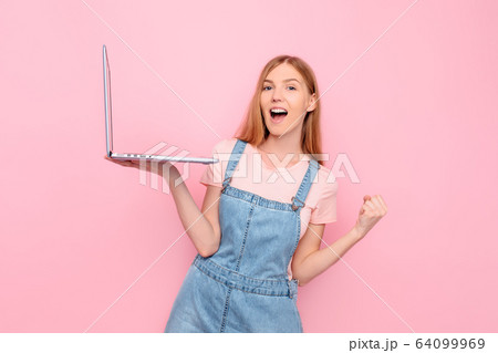 Portrait of a shocked girl holding a laptop and Portrait of a shocked girl holding a laptop and 64099969