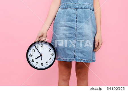 hands holding a wall clock on an isolated pink hands holding a wall clock on an isolated pink 64100396