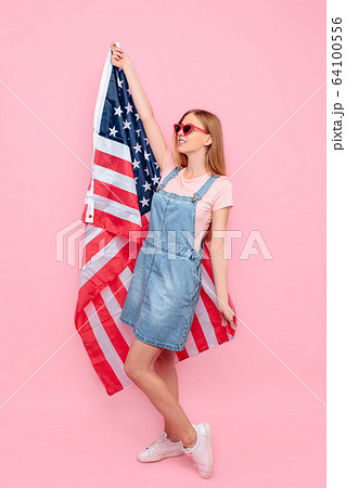woman in sunglasses holding a US flag on an woman in sunglasses holding a US flag on an 64100556