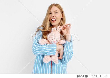 Beautiful teen girl in pajamas hugs a plush toy Beautiful teen girl in pajamas hugs a plush toy 64101298