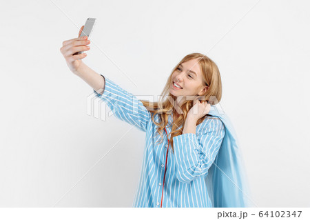 Happy young girl in pajamas holds a soft pillow Happy young girl in pajamas holds a soft pillow 64102347
