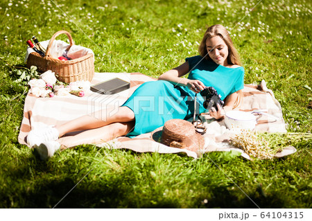 Portrait of happy young woman having rest on picnic in park Portrait of happy young woman having rest on picnic in park 64104315