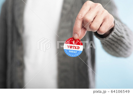 Hand of man holding an I voted today sticker with American Flag Hand of man holding an I voted today sticker with American Flag 64106549