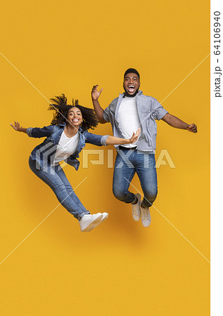 Happy African Couple Fooling Together, Jumping High On Air In Studio 64106940