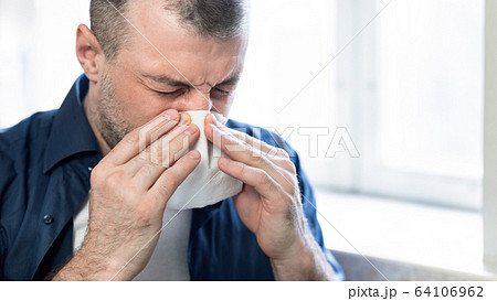 Mature Man Blowing Nose In Paper Tissue Sitting At Home 64106962
