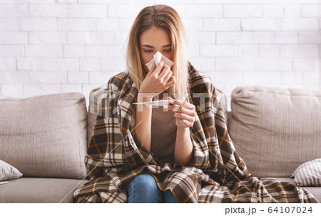 Woman with plaid on shoulders measures temperature 64107024