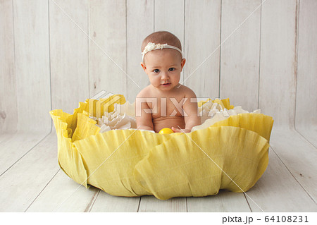 One year old girl sitting in handmade paper green cabbage.  64108231