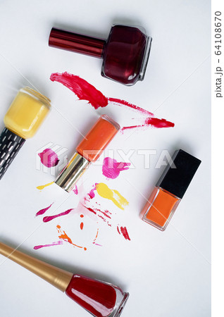 Lucky on a white background, with smears of varnish. Orange, burgundy, red.Choosing varnishes for manicures in a beauty salon. 64108670