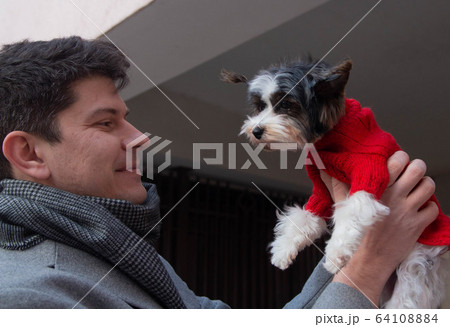 man holds cute small dog taking part in street photoshoot man holds cute small dog taking part in street photoshoot 64108884