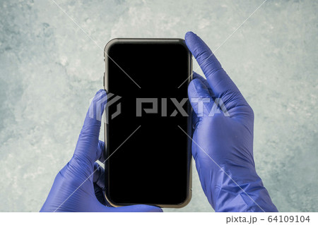 hands with blue latex gloves, holding mobile phone hands with blue latex gloves, holding mobile phone 64109104