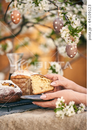 Traditional russian Easter. Woman hands take Orthodox paskha, kulich cakes on table. 64109123