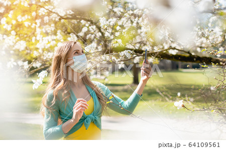 Woman enjoying the spring blossom despite the Coronavirus crisis 64109561
