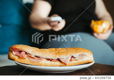 woman eating tons of unhealthy food watching TV 64109756