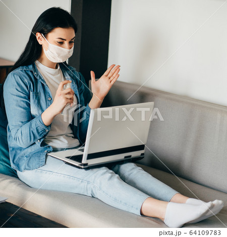 Woman in face mask spreading sanitizer on hands Woman in face mask spreading sanitizer on hands 64109783