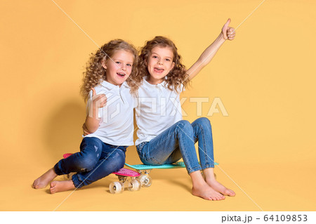 Two Active and happy girls with curly hair having fun with penny board, smiling face stand skateboard. Penny board cute skateboard for girls. Lets ride. Girl with penny board yellow background Two Active and happy girls with curly hair having fun with penny board, smiling face stand skateboard. Penny board cute skateboard for girls. Lets ride. Girl with penny board yellow background 64109853