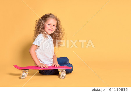 Active and happy girl with curly hair, headphones having fun with penny board, smiling face stand skateboard. Penny board cute skateboard for girls. Lets ride. Girl with penny board yellow background Active and happy girl with curly hair, headphones having fun with penny board, smiling face stand skateboard. Penny board cute skateboard for girls. Lets ride. Girl with penny board yellow background 64110656