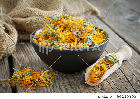 Calendula flowers in bowl, scoop of dry marigolds. Calendula flowers in bowl, scoop of dry marigolds. 64110805