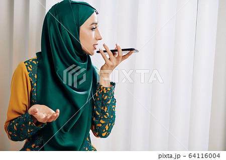 Muslim woman recording voice message 64116004