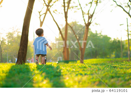 Adorable little asian boy walking on green grass 64119101