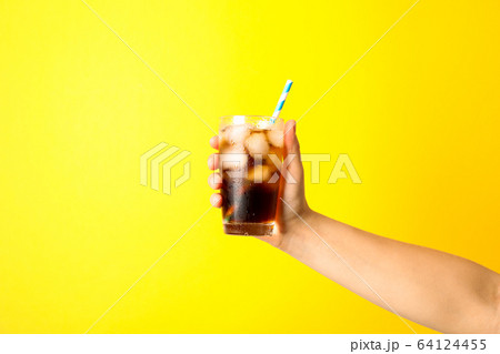Female hand holding a glass with ice cola and Female hand holding a glass with ice cola and 64124455