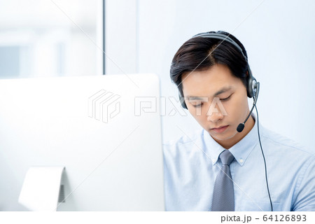 Handsome Asian telemarketing staff concentrating 64126893