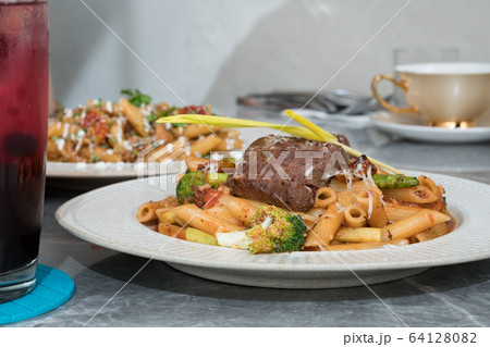 Macaroni with steak and tomato sauce on the table. 64128082