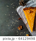 A piece of pumpkin cheesecake on white crumpled paper on a black granite chalkboard with text space 64129498