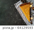 A piece of pumpkin cheesecake on white crumpled paper on a black granite chalkboard with text space 64129593