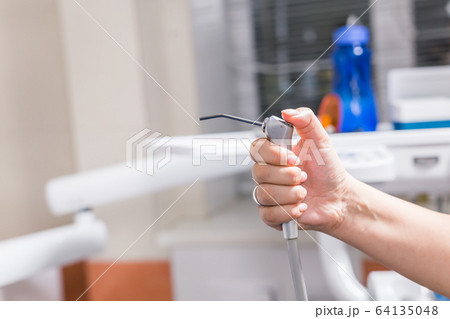 Dentistry, dental health and medicine concept - Close-up of dentist's hand holding a dental tool instrument. Dentistry, dental health and medicine concept - Close-up of dentist's hand holding a dental tool instrument. 64135048