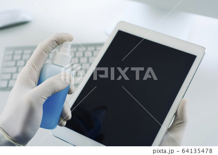 man disinfecting his digital tablet man disinfecting his digital tablet 64135478
