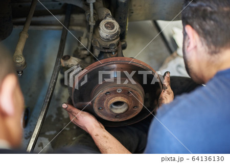 Mechanic with dirty hands repairing car wheel. 64136130
