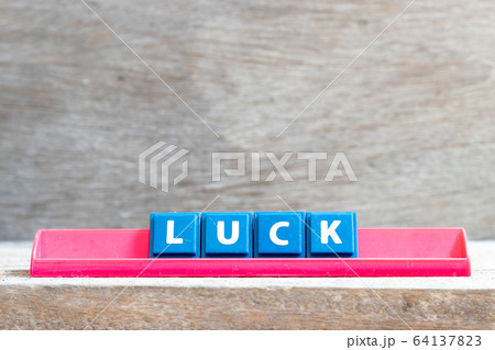 Tile letter on red rack in word luck on wood background Tile letter on red rack in word luck on wood background 64137823