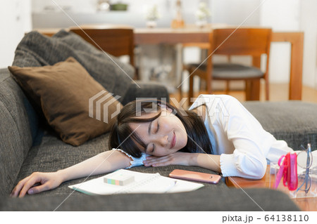 疲れてソファで眠る若い女性 疲れてソファで眠る若い女性 64138110