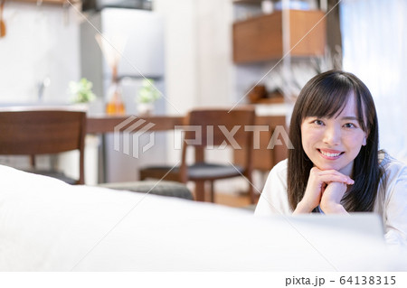 ソファの奥から見つめる若い女性 64138315