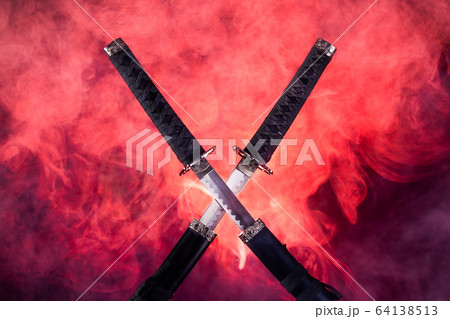 Partially drawn blades of two katanas in red smoke 64138513