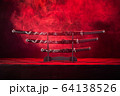 Three swords on stand, red smoke behind 64138526